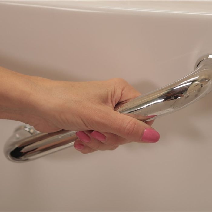 Hand gripping a chrome grab bar mounted on a bath wall