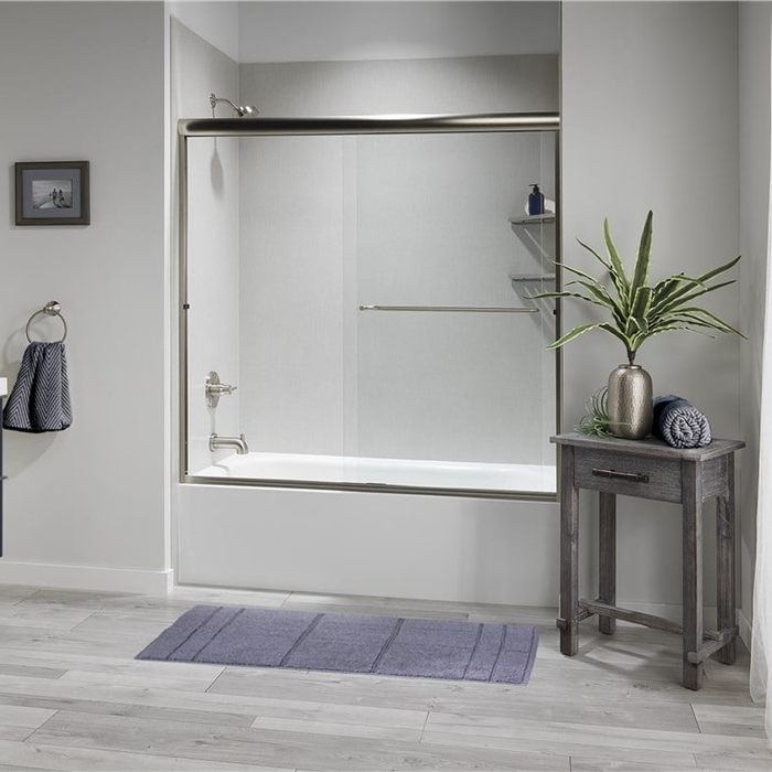Alcove bathtub with sliding glass panels beside a navy vanity